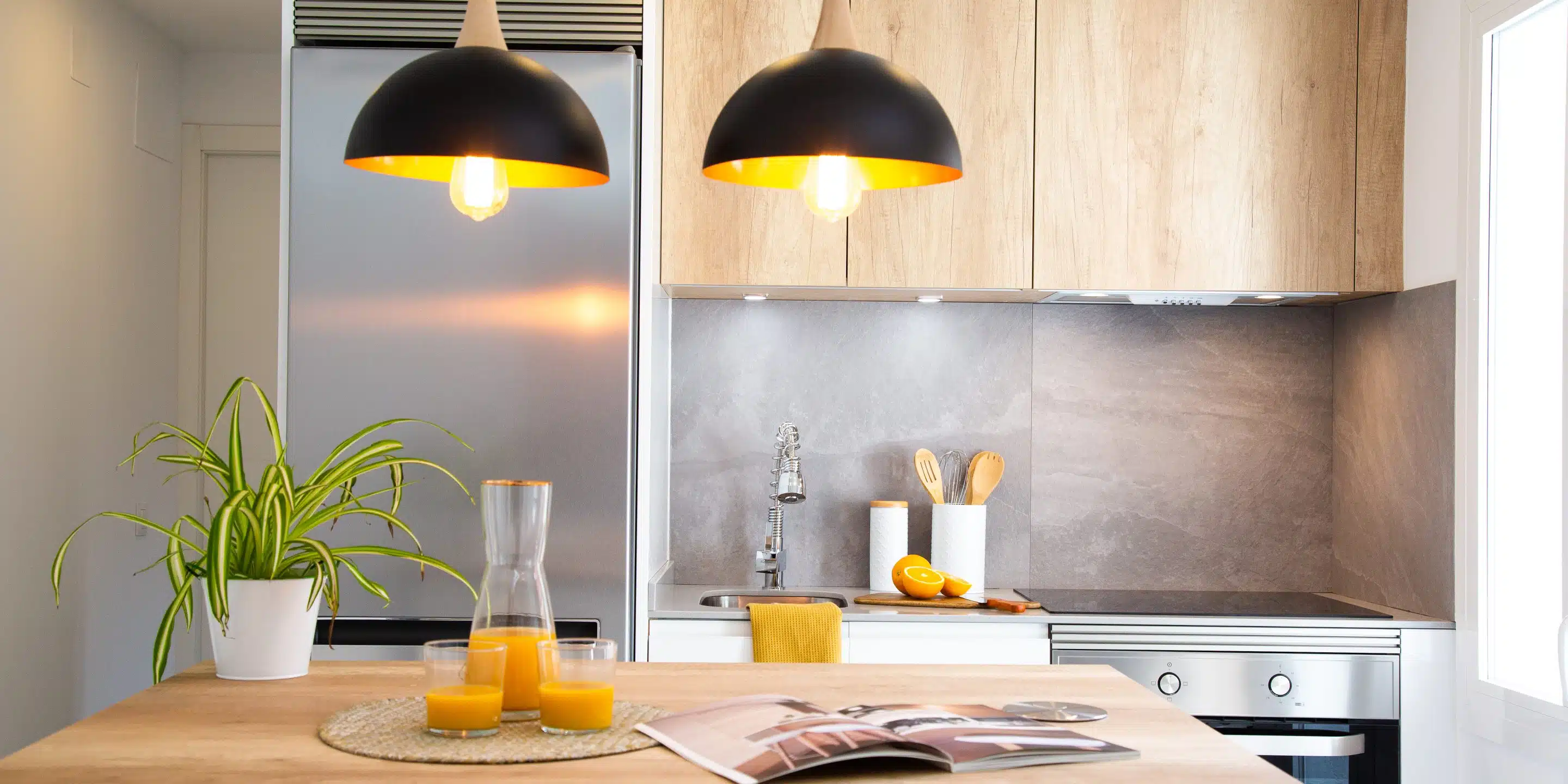 cocina blanca con madera muestra lamparas negras que brindan una luz cálida en el ambiente