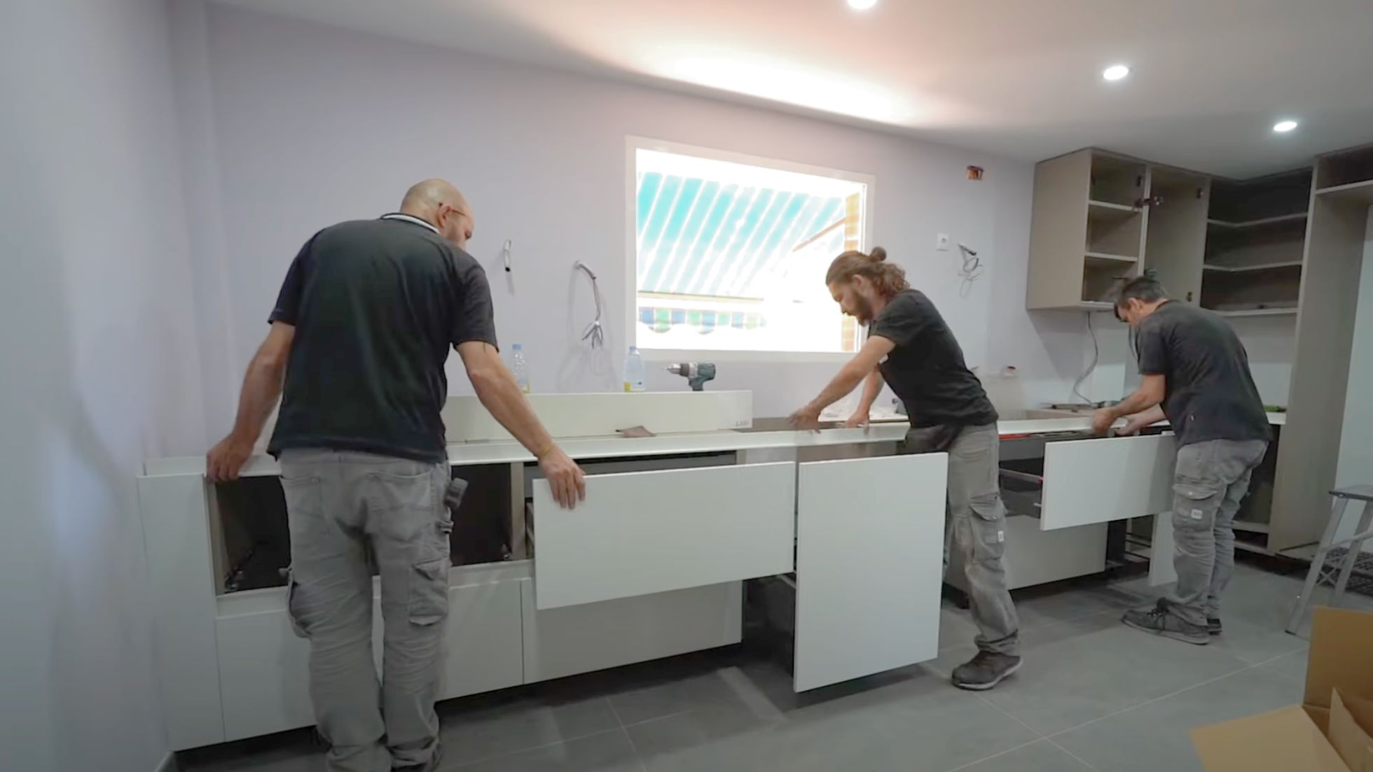 Tres montadores de cocinas de Línea 3 trabajan en el montaje de la cocina de un cliente