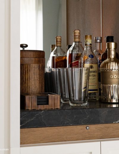 Un mueble bar de piedra negra y madera con botellas de wisky