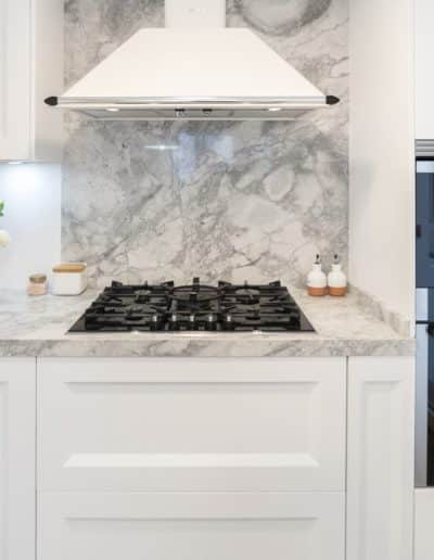 unos fogones de gas en una cocina blanca barquillo con una encimera de portobello