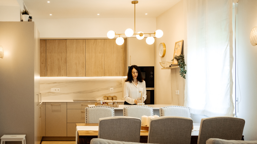 Oro y Sáuco: una cocina abierta con peninsula en madera, cashmere y detalles dorados.