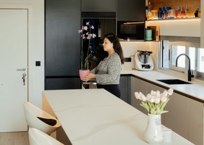 una cocina blanca con isla abierta al salón y la entrada