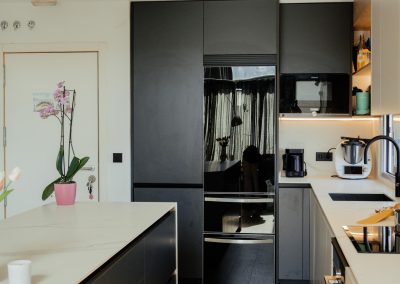 una cocina blanca con isla abierta al salón y la entrada