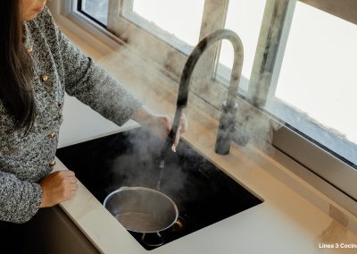 una cocina blanca con isla abierta al salón y la entrada