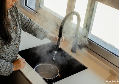 una cocina blanca con isla abierta al salón y la entrada