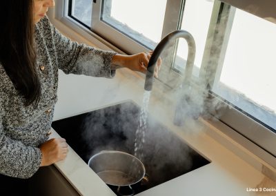 una cocina blanca con isla abierta al salón y la entrada