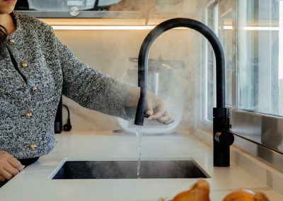 una cocina blanca con isla abierta al salón y la entrada