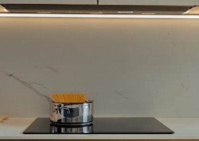 una cocina blanca con isla abierta al salón y la entrada