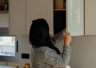 una cocina blanca con isla abierta al salón y la entrada