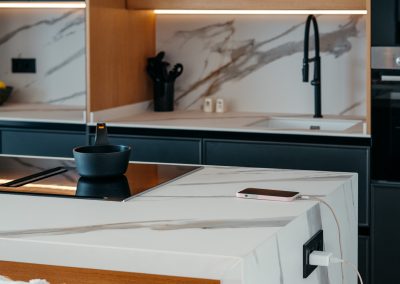 Encimera Porcelánica modelo Sierra Nevada de 1,2 cm de grosor en: ­Espacio desayunador y fregadero con chapado ­Isla con dos costados ingletados , forma irregular efecto cascada + regruesada hasta 6 cm